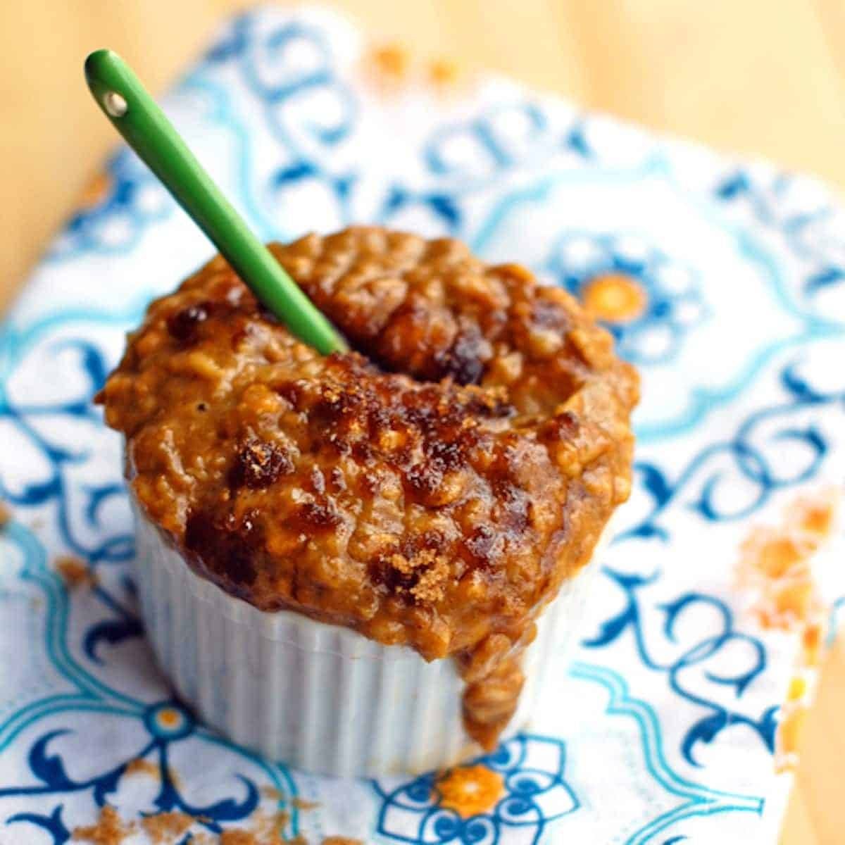 Pumpkin oatmeal with pumpkin, bran, and egg whites in a bowl with a green spoon.